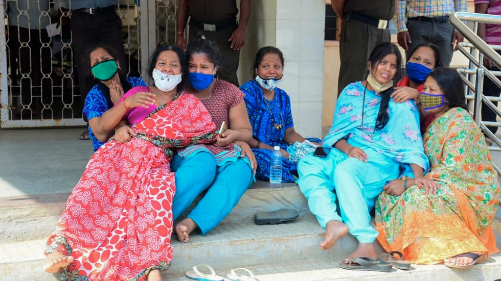 Anhöriga till covidpatienter vakar utanför ett statligt sjukhus i Chamarajanagar i delstaten Karnataka.