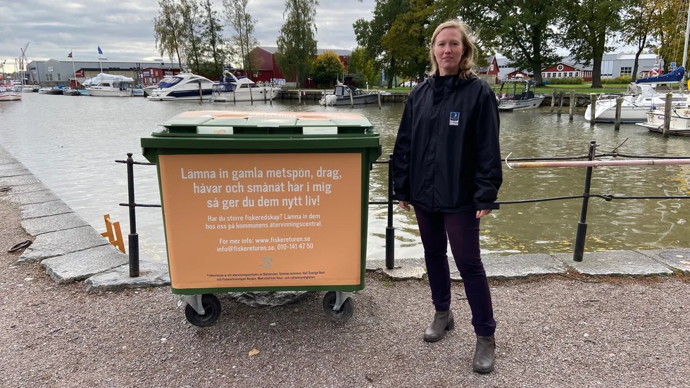 Elin van Dooren bredvid återlämningskärl för fiskeredskap vid Trosaån längs Östra Ågatan intill hamnbassängen. 