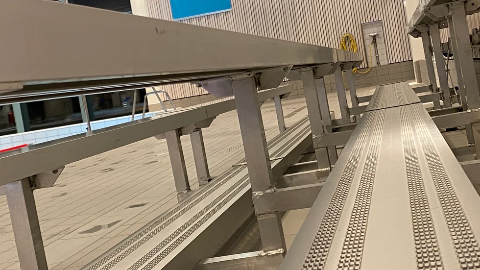 I simhallen står tre sektioner av aluminiumläktaren uppställda. De andra 17, som skulle ha ställts i badets källare, ck inte plats i hissen och har därför fått ställas i ett förråd i ishallen.