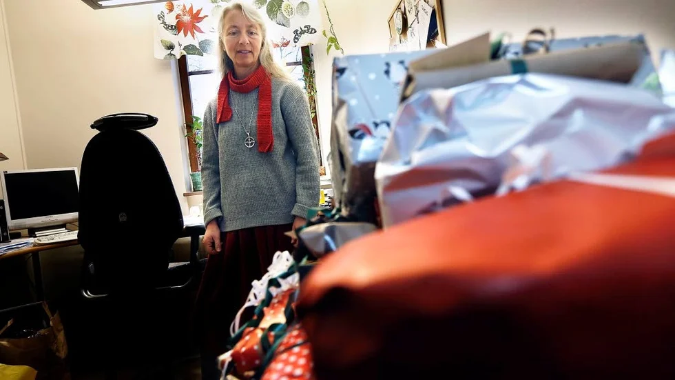 Julklappar i mängder. Diakon Helena Svensson är behjälplig med utdelning.