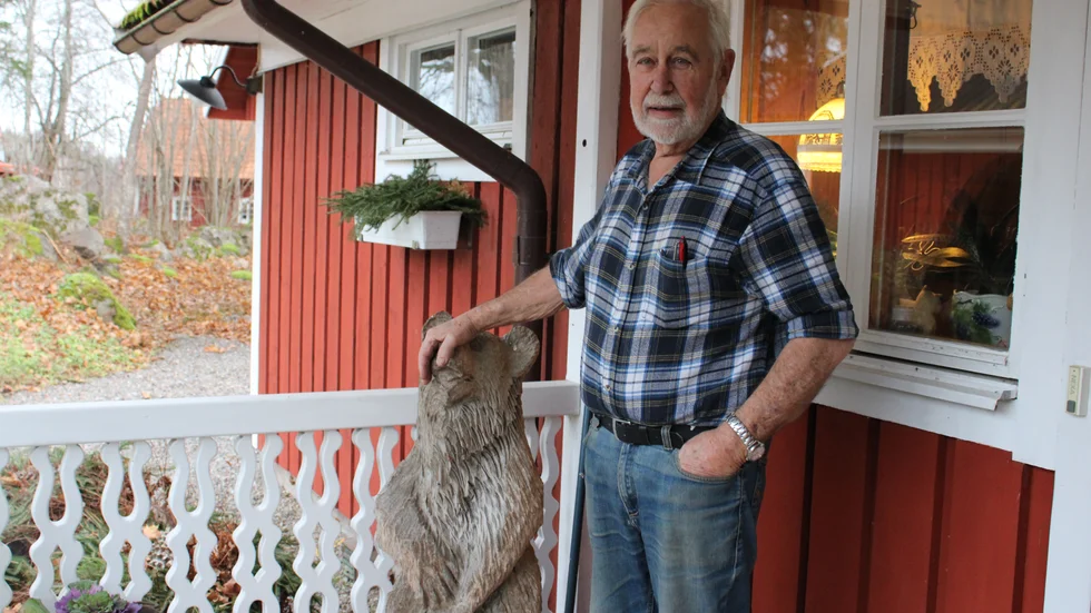 Bo Karlsson på förstutrappan till det hus i Humpen som han och hustrun byggt och byggt ut under de senaste 50 åren. Björnen är en gåva från ett av barnen. 