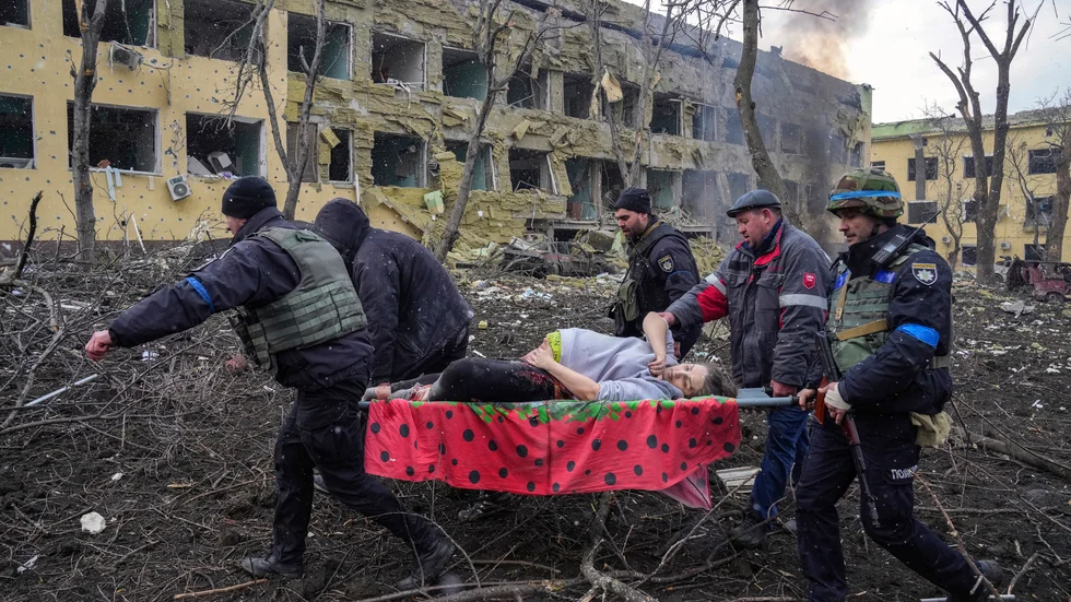 En sårad kvinna bärs ur rasmassorna efter det ryska angreppet på Mariupol.