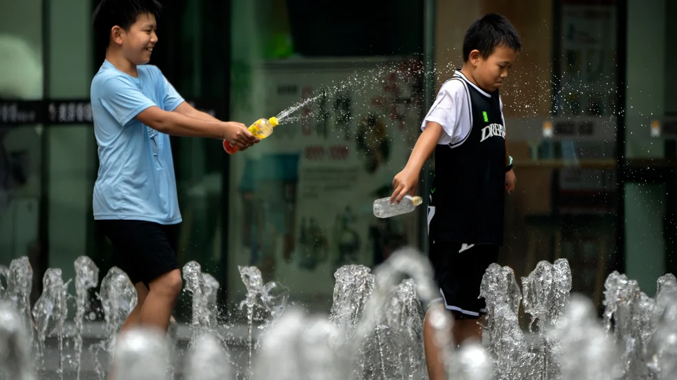 Pojkar svalkade sig vid en fontän i Peking i lördags, när temperaturen steg till runt 40 grader Celsius.
