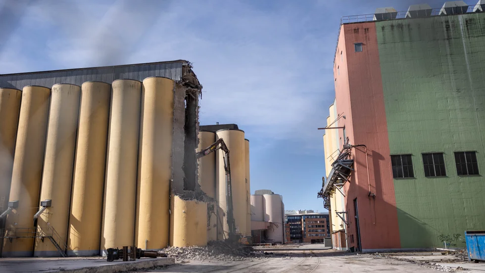 Rivningen av silotornen är igång. Högrivaren knaprar i sig de 30 centimeter tjocka betongväggarna uppifrån och ned. 
