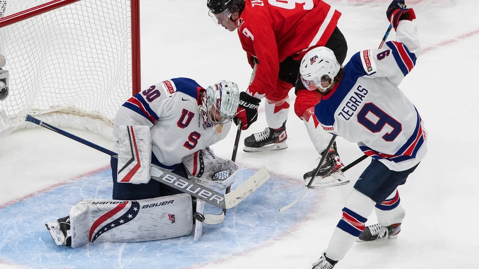 Kanadas Connor Zary stoppas av USA-målvakten Spencer Knight. Trevor Zegras försvarar.