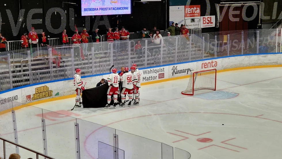 Ludvig Levinsson ligger orörlig på isen. Lagkamrater i Mora håller ett skynke framför den skadade spelaren.