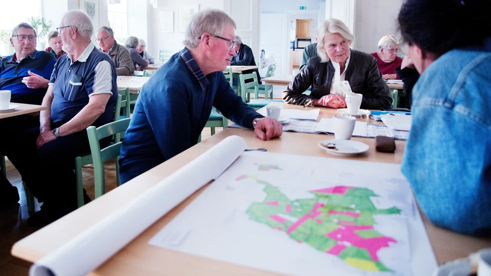 Avslutning för studiecirkeln där Storsudrets ägarförhållanden av jordbruksmark har kartlagts. Birgitta Lundberg sitter vid bordsänden och är en av initiativtagarna. Kartan över Sundre är i förgrunden, där grön mark ägs av de som är bofasta, röd mark ägs av de som inte är det och gul mark av kyrkan. 