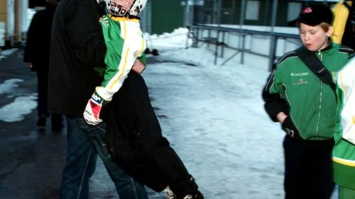 Patrik Karlsson, tränare och pappa, bär ut Jonas Lundgren till matchen. Jonas är den ende av grabbarna i Fredriksbergsskolans klass 3 som inte spelar vare sig hockey eller bandy.