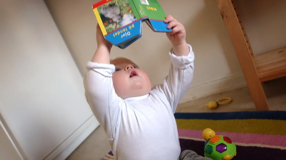 Tiomånaders gosse läser bok. Arkivbild.