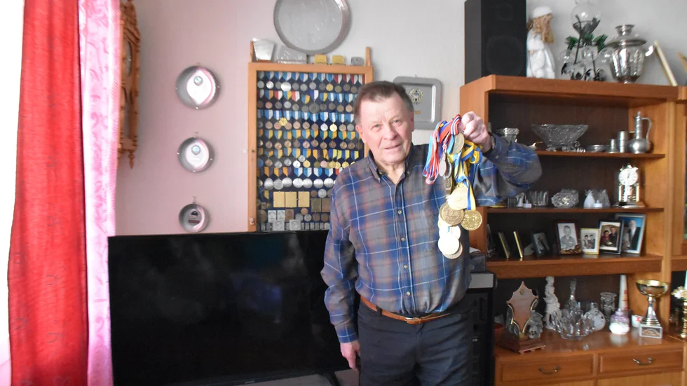 Börje Oskarsson visar stolt upp sina medaljer från sin tid som aktiv skidåkare men berättar med en stor uppgivenhet om hur han nu missar hela VM på tv.