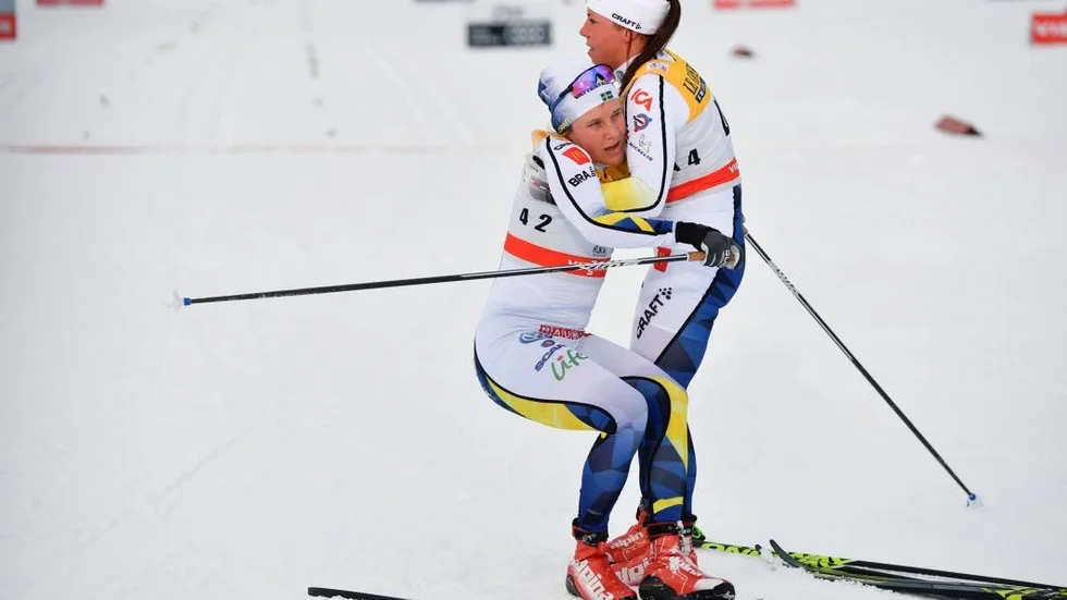 Sveriges Charlotte Kalla tar emot en trött Hanna Falk under damernas 10 km klassisk åkning  vid världscupen i Ruka i Finland på lördagen.