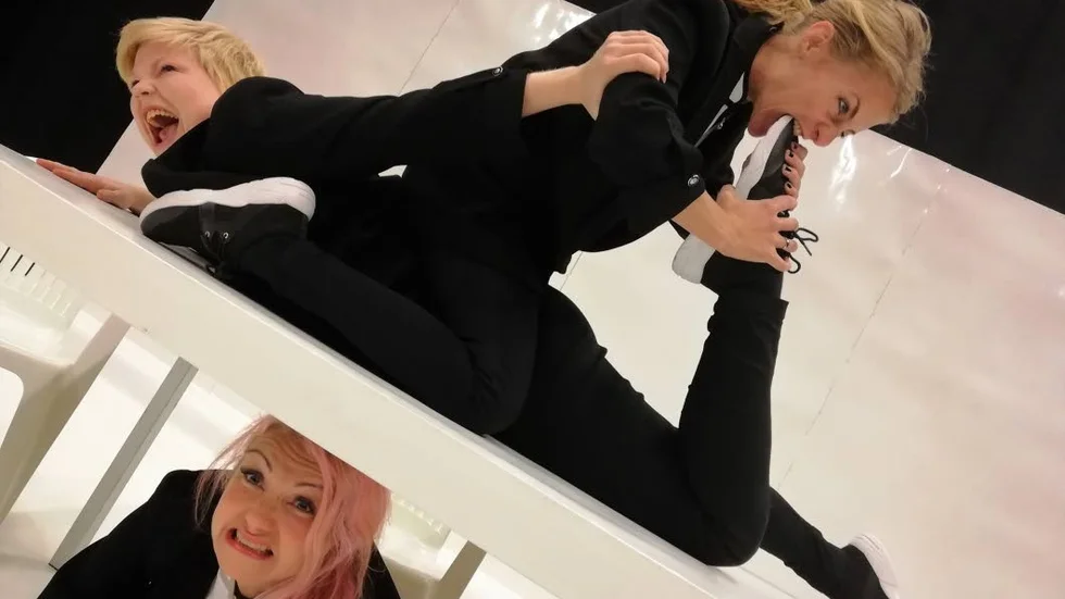 Ensemblen i "Du skrattar faktiskt också" utforskar gränserna mellan skämt och allvar, fr v Johanna Westlin och Sofia Gabrielsson, AnneLee Vikner under bordet.