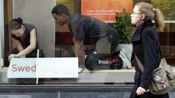 Janna Tabla och Khalid Abdullah klistrar upp nya dekaler i Swedbanks fönster.