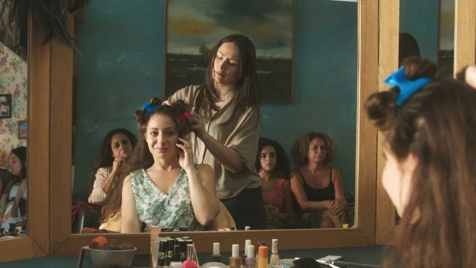 Förväntan. Den blivande bruden Salma, spelad av Dina Shebar, friseras av Christine, gestaltad av Victoria Balitska i den palestinska filmen "Salongen"