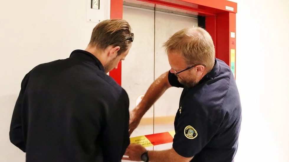Brandtjänstemän tejpar och spärrar av en annan hissdörr som gått sönder. Bilden är inte tagen på Arlandaområdet.