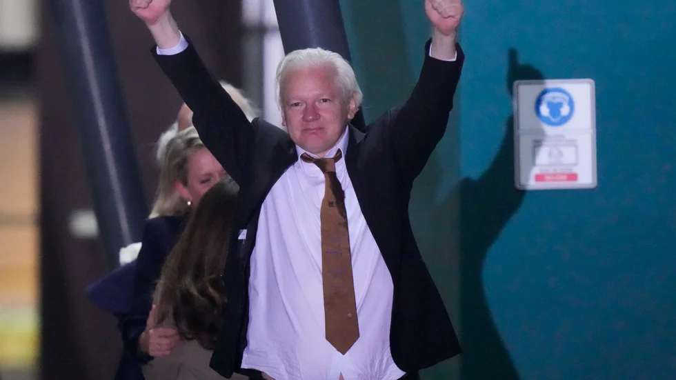 Julian Assange gör dubbel tumme upp efter att ha klivit av flygplanet i hemlandet Australien.