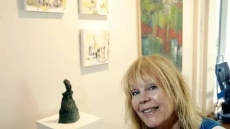 Brittlouise Landfors med bronsfiguren "Beaten", målningarna "Towards the unknown" i olja och tusch samt oljemålningen "Red angel" i bakgrunden.