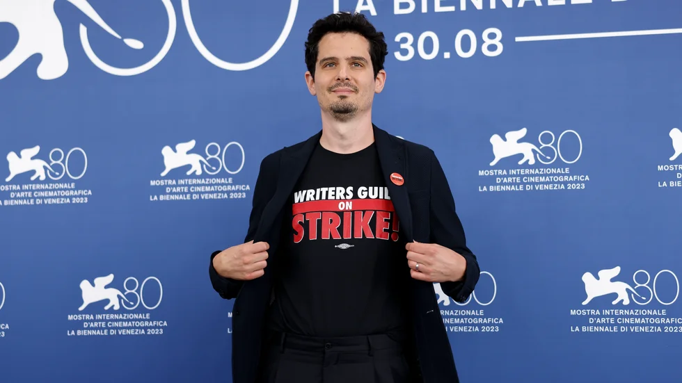 Juryns ordförande Damien Chazelle bär en t-shirt med texten "Writers Guild on strike" när han poserar för fotografering under filmfestivalen i Venedig. Chazelle säger att han helhjärtat stöder strejken i Hollywood.