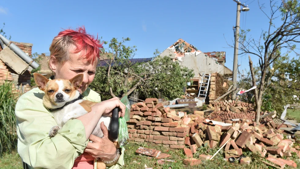 En kvinna med en hund i famnen gråter framför familjens förstörda hus i byn Moravská Nová Ves.