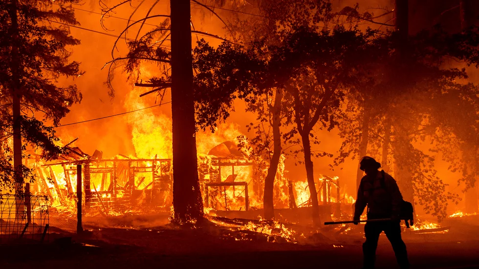 En brandman passerar ett brinnande hem i Plumas County, Kalifornien, den 24 juli.