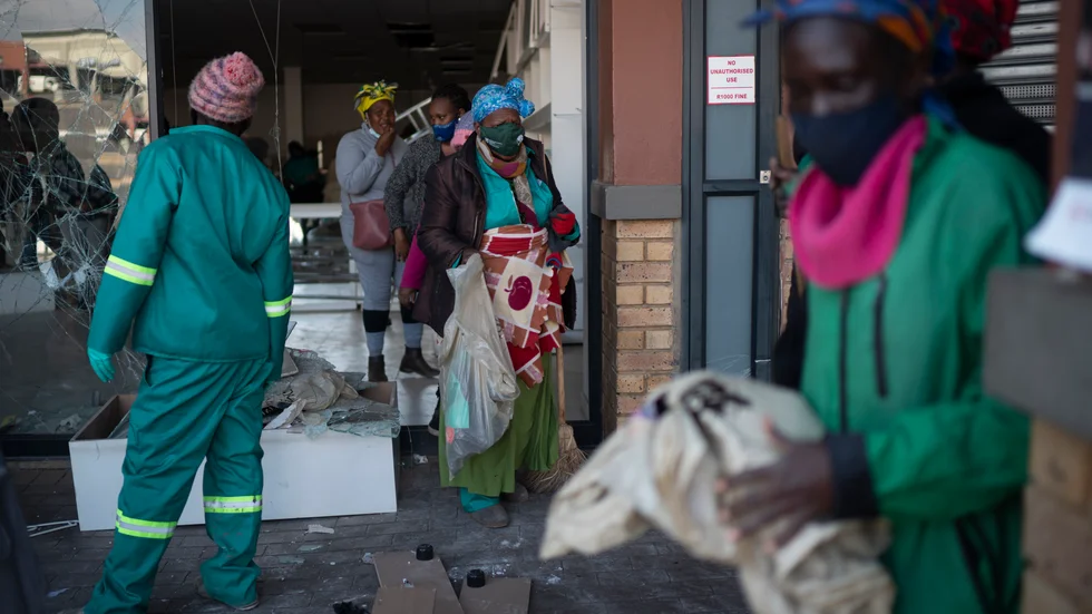 Volontärer röjer upp bråten vid ett köpcentrum som plundrats i sydafrikanska Soweto. Arkivbild.