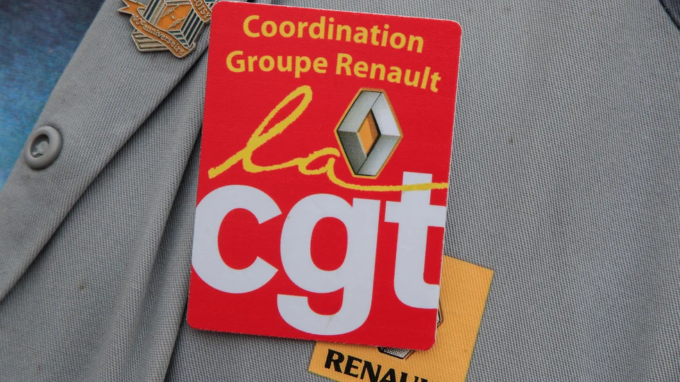 En Renault-anställd med fackförbundet CGT:s på sina arbetskläder under en protest mot uppsägningar vid en bilfabrik utanför Paris i juni 2020. Arkivbild.