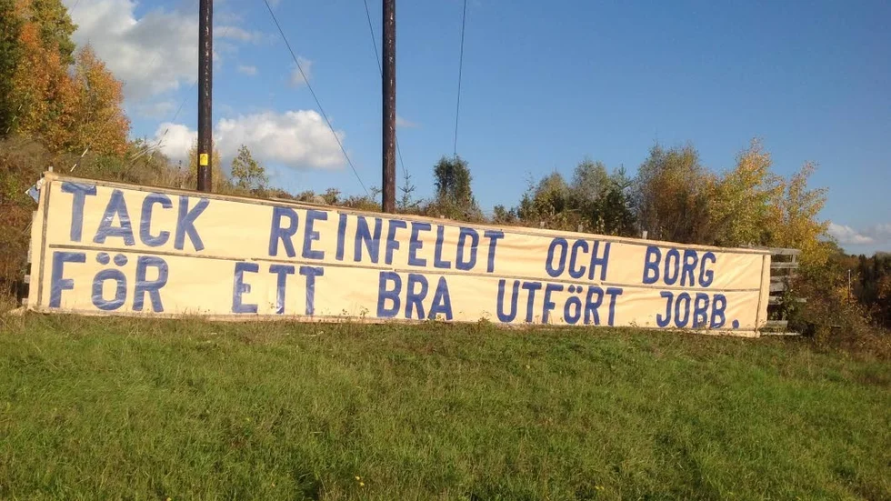 Borgerlig hyllning. Håkan Thornell,  före detta centerpartist, men numera socialdemokrat, hyllar Reinfeldt och Borg i den tidigare borgerliga regeringen, på sin nya skylt vid E 4-an.