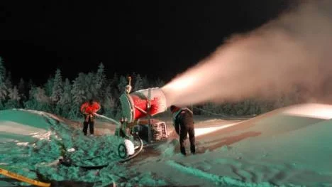 Snökanonen spyr ut snö. Det ska bli perfekt underlag till torsdagskvällens skotertävlingar. Patrik Hermansson och Joel Westerlund håller koll och vet hur en bra bana ska byggas.