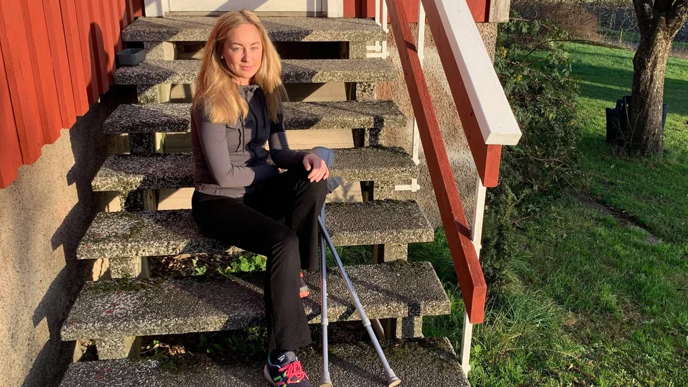 Långtidssjuka Caroline Lööf på trappan framför huset med hennes ofrivilliga följeslagare, kryckorna. 