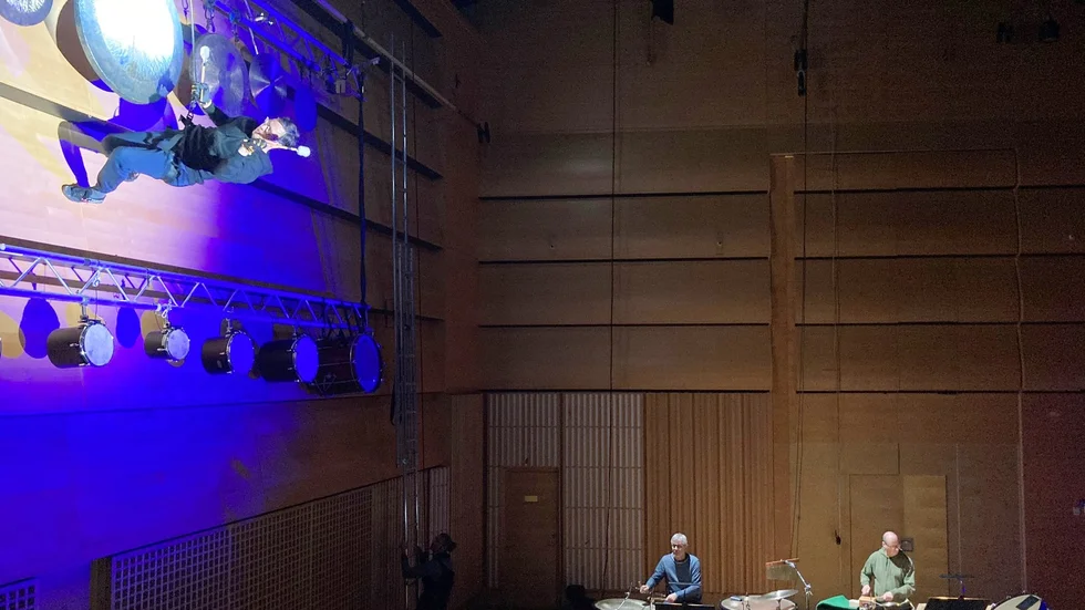 Hängande i en lina på väggen spelar SON:s slagverkare Martin Orraryd det nyskrivna stycket tillsammans med orkesterkollegorna Lars Gärd och Anders Dahlstedt.