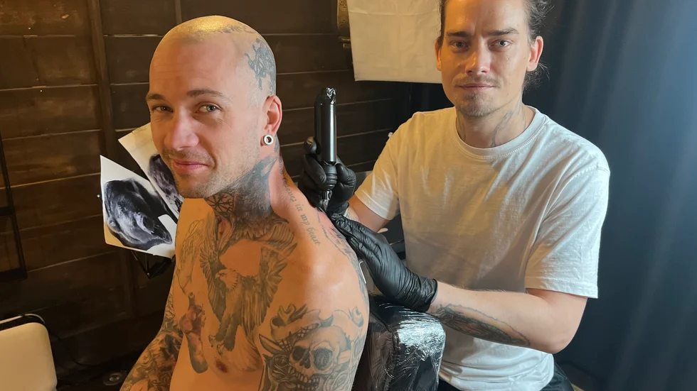 Här sitter han tillsammans med Rasmus Hedlund som har bokat tid för att täcka över en tatuering.