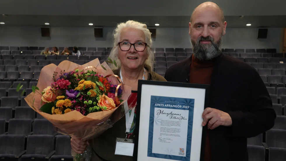 Karin Åhström, ordförande i Folkets husföreningen i Hargshamn, jublar över utmärkelsen Årets arrangör 2023. Calle Nathanson, vd Folkets Hus och Parker, överlämnade blommor och prischeck.