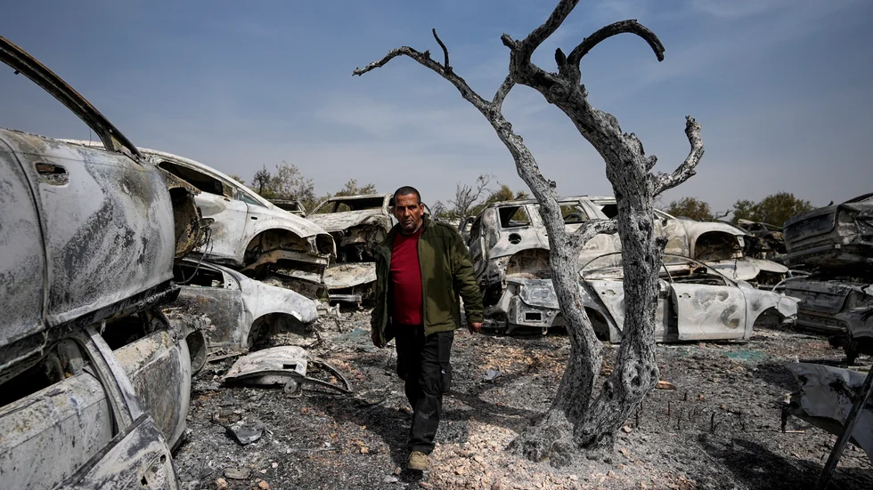En palestinsk man går bland utbrända bilar i staden Hawara.