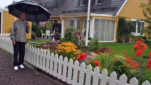 Regn och rusk. Owe Stefansson får ta fram det stora paraplyet när han visar runt i sin välskötta trädgård.