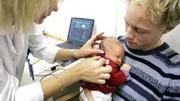 Melvin Wandebäck, fem dagar gammal, sover i pappa Daniels famn medan audionomen Svetlana Barinova Masich sätter in den lilla mätproben i hans öra.