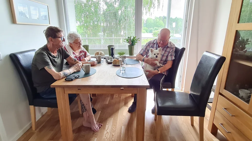 Hans och Eva Skogh, och Bengt Andersson ses hemma hos paret för att diskutera att hissen inte fungerar längre. 