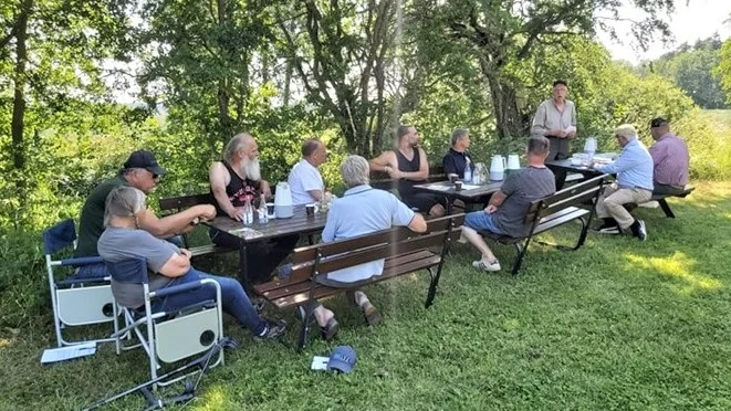 Deltagare vid årsmötet i Gothemåns Vattenråd trycker i värmen. Bertil Hanell från sockenföreningen informerar om Hästsund och vandringsslingan längs Dalhemån.