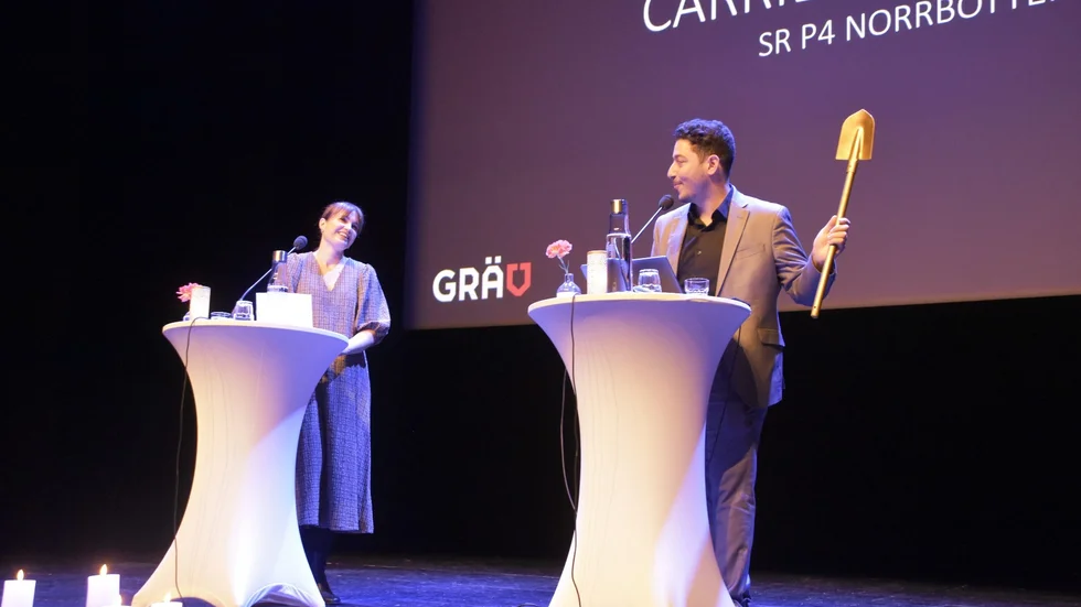Carrie Söderberg från P4 Norrbotten får överta spaden och ansvaret som grävgeneral inför 2022 års konferens av Fouad Youcefi, ordförande för Föreningen Grävande Journalister.