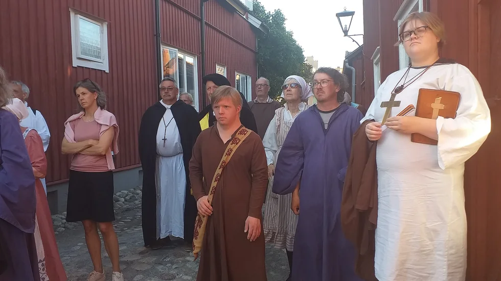 Eskil (Ellen Rudborg), munken och en grupp brandungar lyssnar på Augusta Widebeck.
