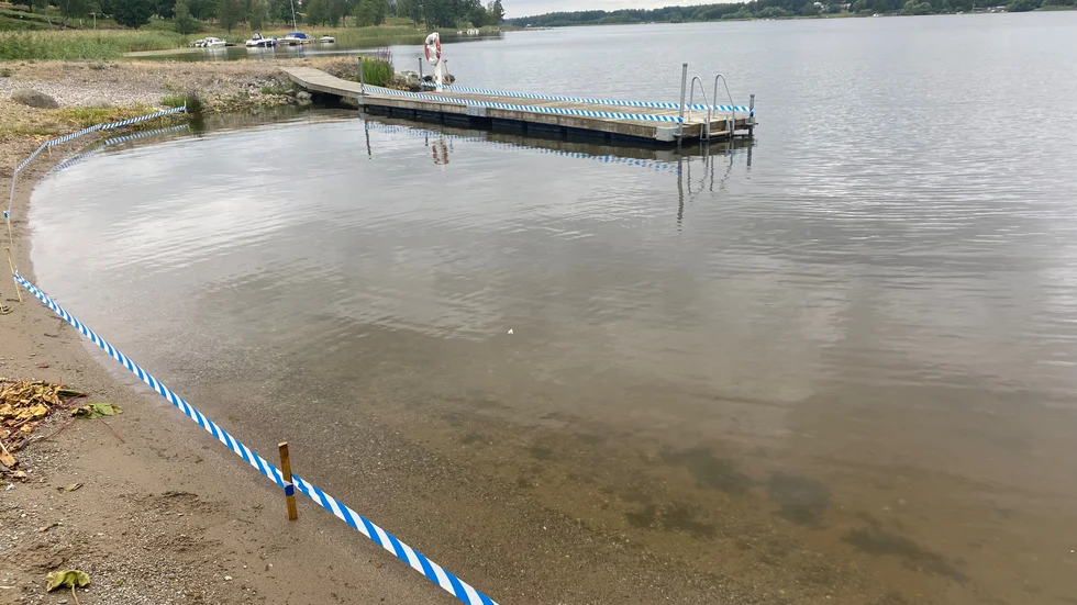 Vid Sundby strand i Stallarholmen har man satt upp ett plastband längs strandkanten för att gässen inte ska komma upp och skita ned stranden.