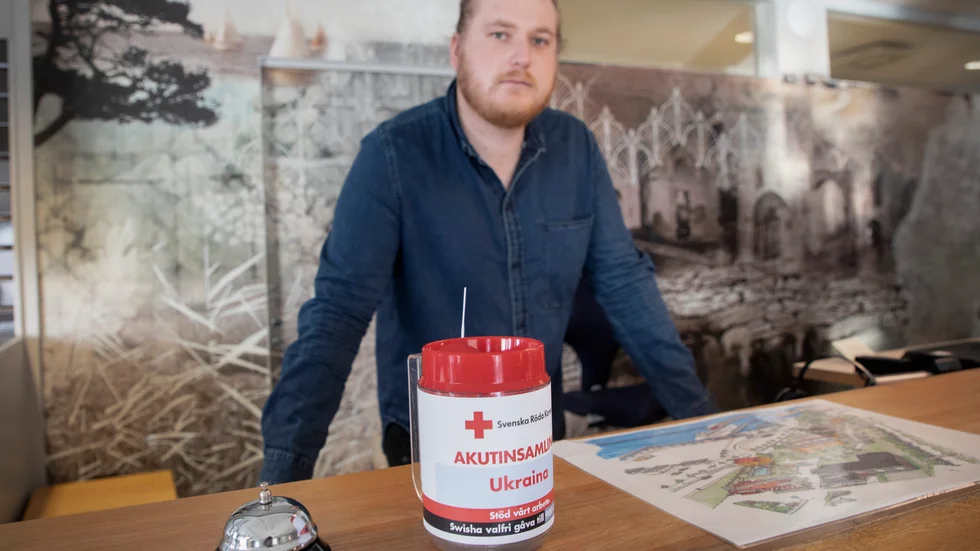 Scandic i Visby är ett av flera företag på Gotland som hämtat en bössa hos Röda Korset för den akuta insamlingen till Ukrainas folk. Simon Vernersson står bakom receptionsdisken på hotellet.