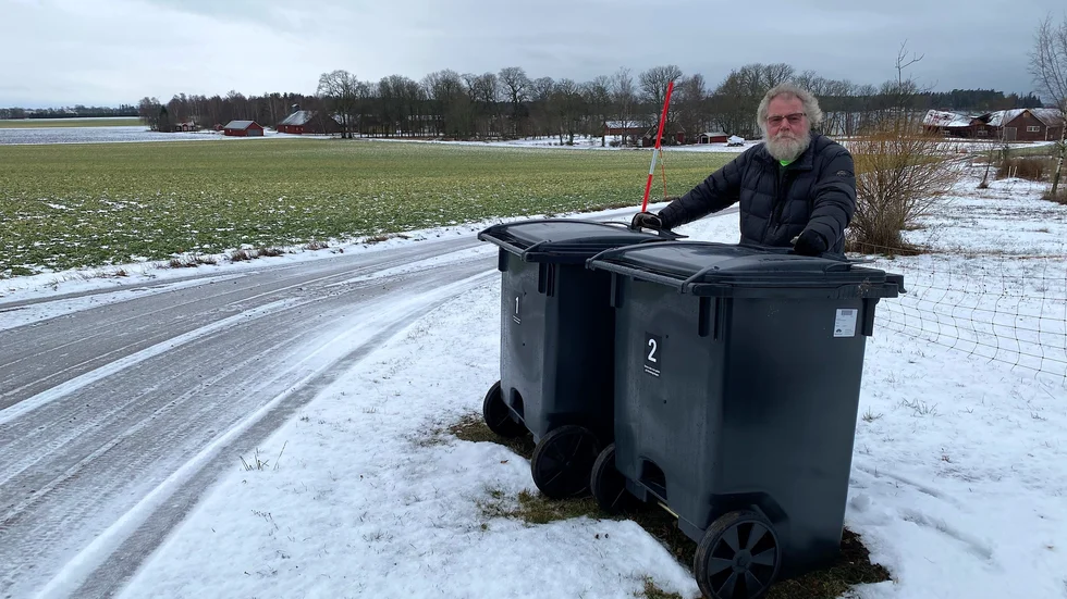 Christer Johansson vid soptunnorna som står vid infarten till bostaden. Numera ska soptunnorna placeras cirka 600-700 meter från hemmet under vintern – ungefär vid den röda ladugården som skymtas långt bak till vänster.