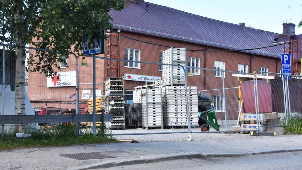 Från Södra Järnvägsgatan sett skymtar entrén till Röda korset bakom stängsel och byggmaterial.
