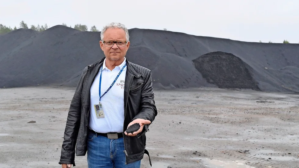 Lars Pettersson visar en näve järnsand och i bakgrunden det stora lager som Skellefteå kommun köpte för flera år sedan. Foto: Yvonne Rönngren.