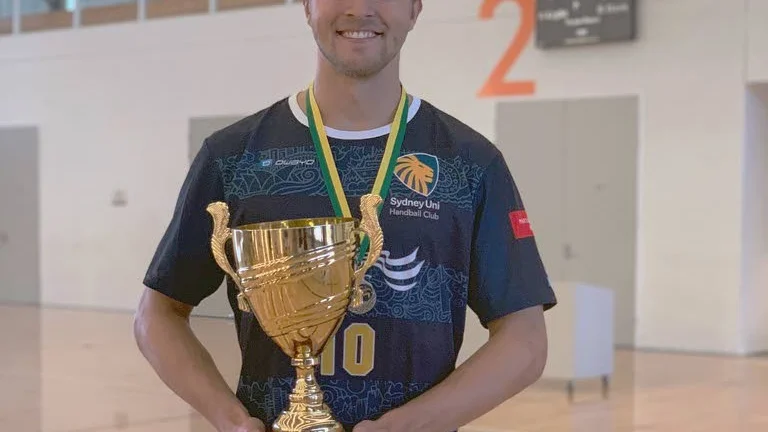 Isak Wallin stoltserar med bucklan som innebär att han och hans lag kan titulera sig som bästa lag i Oceanien.