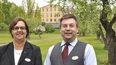 Hotellchefen Birgitta Holmlund och guiden Mats Gustafsson i äppeträdgården framför Krusenbergs Herrgårds huvudbyggnad.