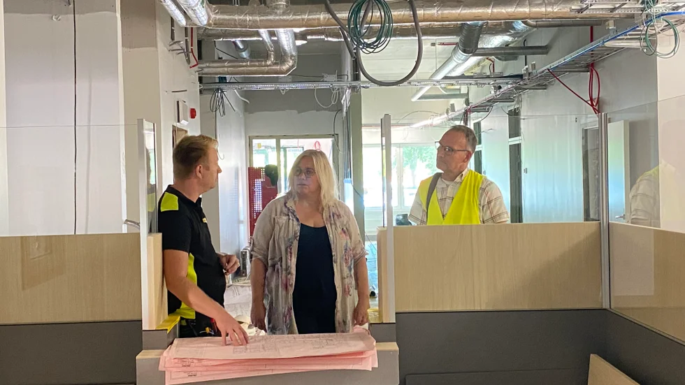 Gamleby hälsocentrals verksamhetschef Maria Nilsson i samspråk med elektrikern Fredrik Roth och Bostadsbolagets projektledare för bygget Casper Rosén. Bilden är tagen inifrån den nya hälsocentralens reception.