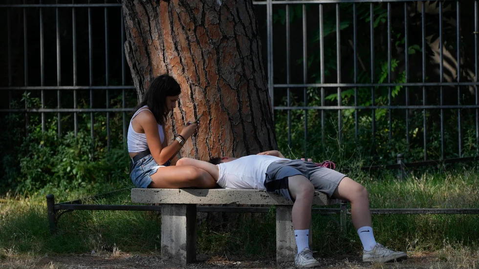 Linne och shorts kanske känns bekvämt i värmen men är inte den lämpligaste klädseln i hettan. Här har ett par sökt sig till skuggan under ett pinjeträd i den italienska huvudstaden Rom tidigare i juli.