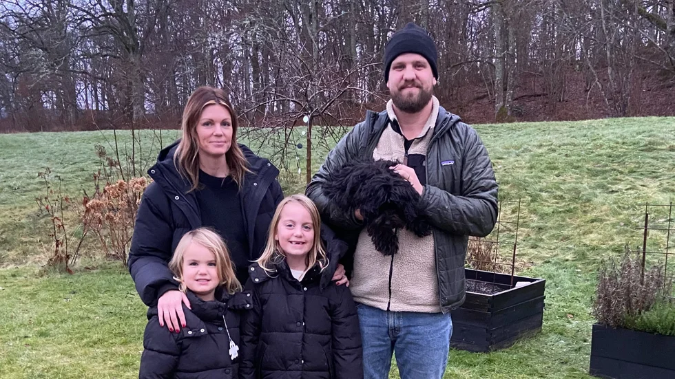 Frida Eriksson och Andreas Strömberg tillsammans med döttrarna Wilma och Freja samt hundvalpen Bosse. I bakgrunden syns ängen som Frida fastnade för direkt vid ett besök i Mariehovsviken sommaren 2022.