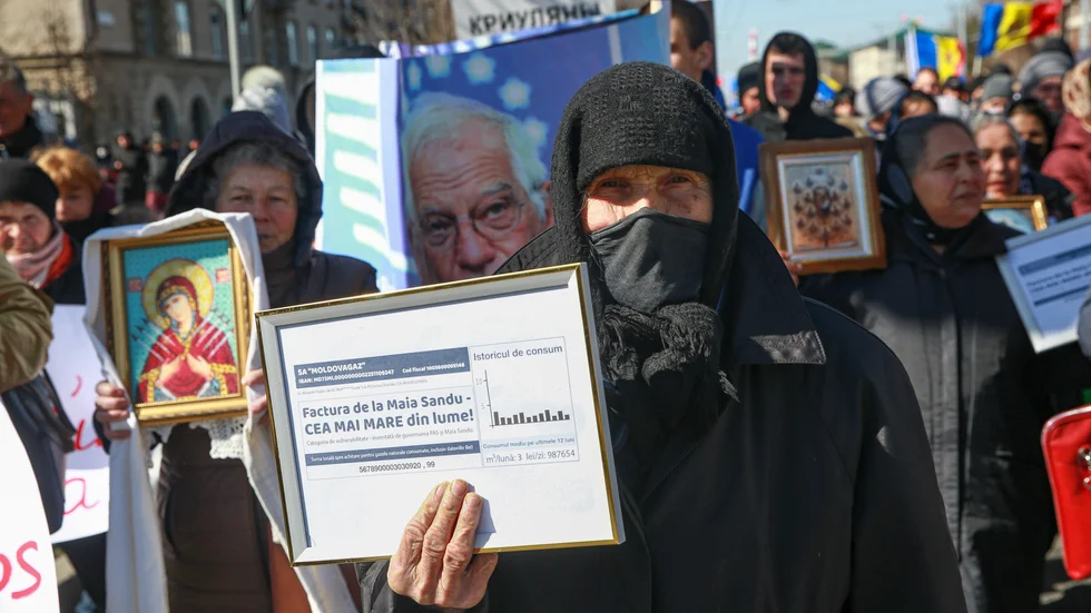 En äldre kvinna håller upp en inramad elräkning under en regeringskritisk protest arrangerad av den proryska oligarken Ilan Shors parti. Bilden togs i Chisinau i Moldavien den 12 mars.